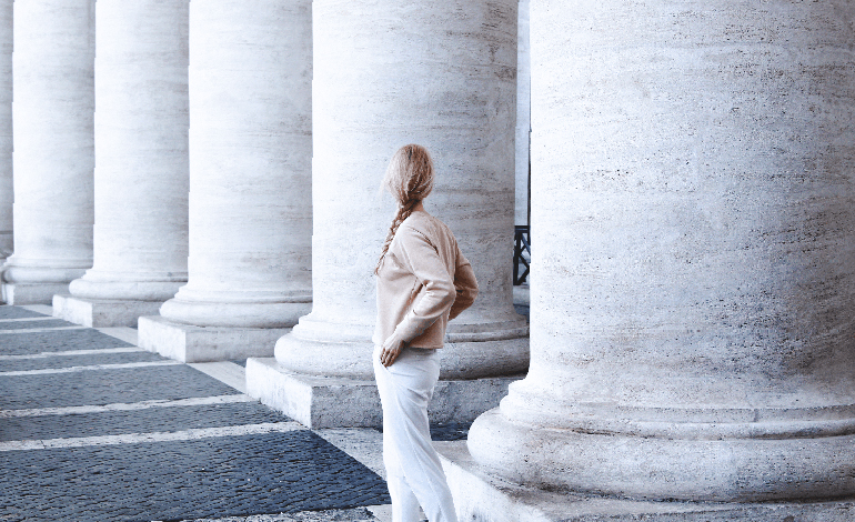 The pillars of health. A woman looking at big classical concrete pillars