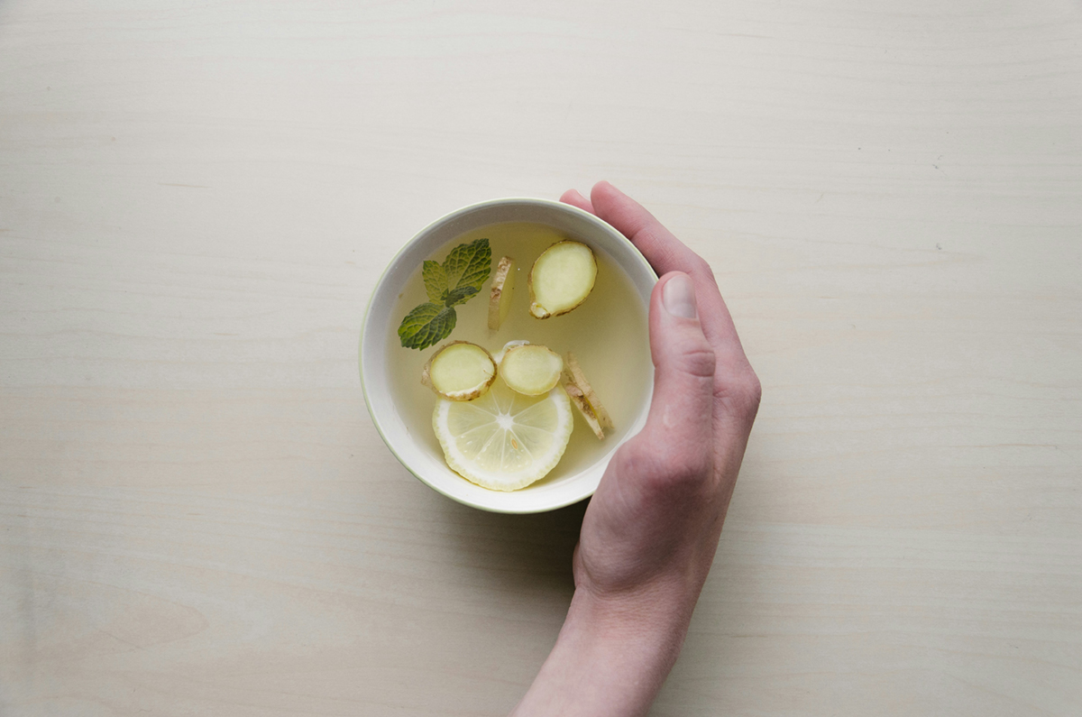 A hand holding a cup of ginger, mint and lemon tea